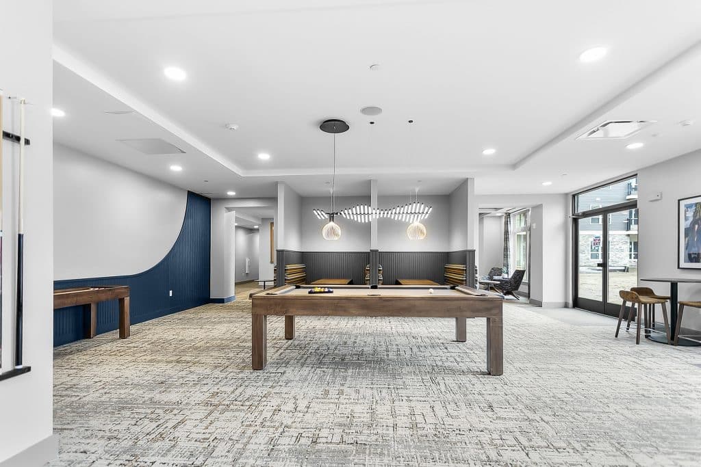 Game room at Triton Square with pool table, shuffleboard, pendant lighting, and seating area